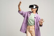 © DimaBerlin - Teenage girl using virtual reality headset. Teenager testing vr grasses isolated on studio gray background. VR, future technology, gadgets, online gaming, training, exploring cyberspace, video game