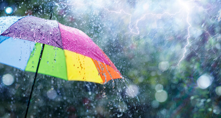 Wall Mural - rain on rainbow umbrella - weather concept - spring and fall shower with abstract defocused drops an