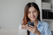© PhotosD - Asian woman holding smartphone, businesswoman using smartphone for social media and messaging with friends, using smartphone to send work email. Concepts of communication via the internet.