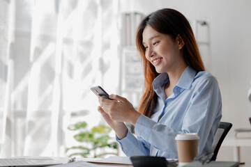 Asian woman holding smartphone, businesswoman using smartphone for social media and messaging with friends, using smartphone to send work email. Concepts of communication via the internet.