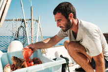 Concentrated Fisherman Near Container With Fish