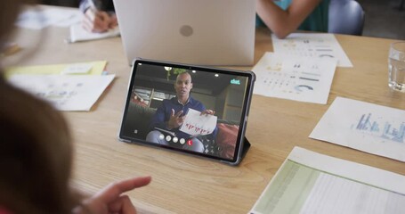 Canvas Print - Caucasian businesswoman on tablet video call with african american male colleague on screen