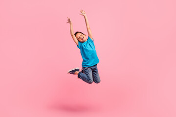 full length photo of impressed cheerful small boy wear blue t-shirt rising hands arms jumping high i