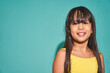 © ADDICTIVE STOCK - Happy ethnic girl child standing against turquoise backdrop