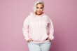 © dinastya - Full body portrait of plus size model woman wearing sport hoody on flat pink background, copy space. Store sportswear of all sizes, bodypositive.