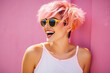 © Маргарита Вайс - Portrait of a young charming alternative style pink short-haired woman wearing yellow sunglasses and a white tank top on a pink wall background.