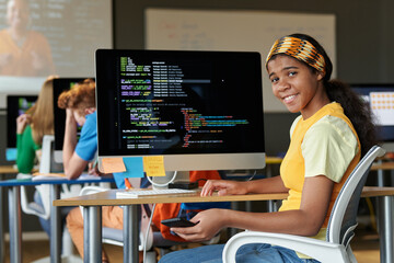 Portrait of African American student smiling at camera while learning IT in the classroom