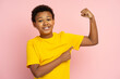 Portrait of smiling confident strong African American teenager pointing finger at biceps