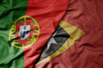 Wall Mural - big waving national colorful flag of portugal and national flag of east timor .