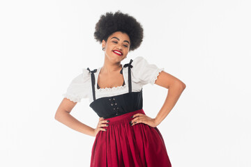 Wall Mural - cheerful african american waitress in bavarian costume with hands on hips on white, oktoberfest