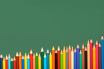 multicolored pencils on green chalkboard background, back to school concept and growth to knowledge, copy space
