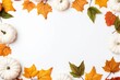 Yellow and green dried leaves and small orange pumpkins on white background, top view, copy space. Halloween, Thanksgiving holiday concept.