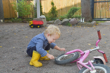 Wall Mural - a boy child repairs a bicycle wheel with a wrench, photo without filters