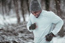Young And Athletic African American Man Jogging During Winter And Snow In An Outdoor Park During Winter And Snow