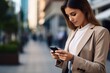 © Marco - Business Frau sieht auf Ihr Smartphone. Frau in der Stadt spielt mit dem Handy und wartet.