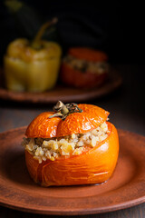 Poster - Close view of homemade juicy tomato stuffed with rice and baked until soft served on plate on dark brown wooden table as part of gemista traditional greek recipe of filled roasted healthy vegetables