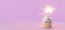 Tasty Birthday Cupcake With Sparkler On Lilac Background With Space For Text