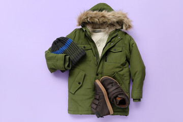 Wall Mural - Children's winter jacket, hat and shoes on lilac background