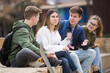 © JackF - Cheerful teenagers sitting together, talking and having fun outdoors