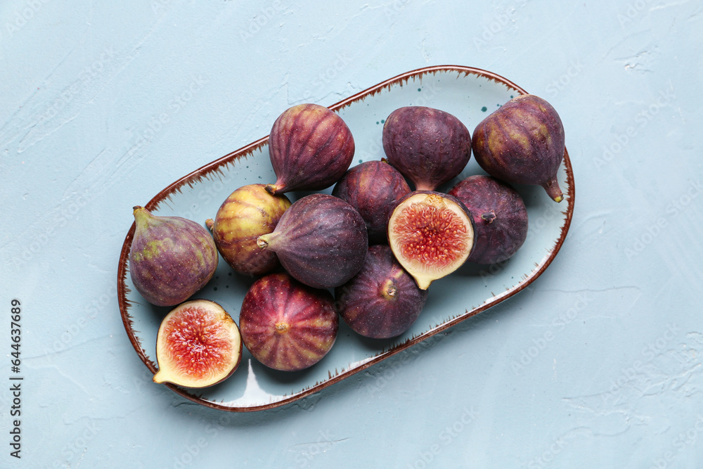 Plate with fresh ripe figs on blue background