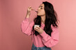 © Nataliya - Waist-up portrait of a young woman snacking on the yogurt with a spoon from the plastic cup during the studio photo shoot. Healthy diet concept