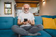 © Miljan Živković - one senior man with headphones use smsrtphone to play music at home