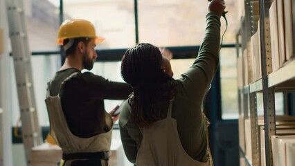 Wall Mural - Hardworking warehouse employees completing orders for delivery, walking through storage site aisles and using digital device to check shipping info while scanning labels on stashed items