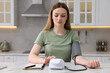 © New Africa - Woman measuring blood pressure with tonometer in kitchen