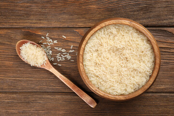 bowl and spoon with white rice on wooden table, flat lay