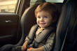 Child toddler boy sitting in a car in the back seat in a child car seat. Baby sitting in baby car seat during car trip. Happy kid in a child car seat wearing a seatbelt while traveling by car.