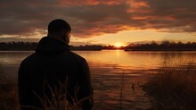 African American man looking out at a lake horizon at sunset