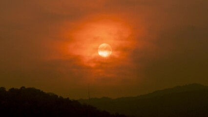 Wall Mural - Time lapse of the sun setting over hills that are covered with clouds, in the style of smokey background.