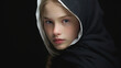 © Daniel L - A studio fashion portrait of a young blond girl wearing a hooded black outfit. Black background.