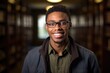 © Baba Images - Smiling portrait of a happy young african american male student in a library of a college or university