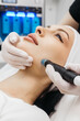 © wedmoments.stock - Professional dermatologist in medical gloves doing hydro peeling procedure for beautiful woman patient in cosmetology clinic. Close up facial treatment.
