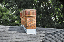 An Old Chimney On A Shingles Rooftop.