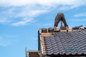 Wall Mural - craftsman on the roof of a family house, building a roof covering from ceramic tiles, copy space