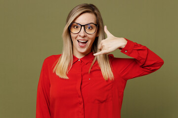 Wall Mural - Young surprised shocked happy woman she wears red shirt casual clothes glasses doing phone gesture like says call me back isolated on plain pastel green background studio portrait. Lifestyle concept.