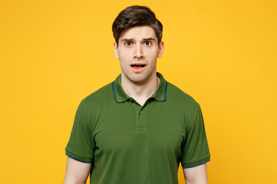 Young sad shoced scared astonished stupefied caucasian man he wears green t-shirt casual clothes look camera with opened mouth isolated on plain yellow background studio portrait. Lifestyle concept.