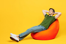 Full Body Side View Young Fun Happy Man He Wears Green T-shirt Casual Clothes Sit In Bag Chair Hold Hands Behind Neck Take Nap Isolated On Plain Yellow Background Studio Portrait. Lifestyle Concept.