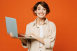 © ViDi Studio - Young surprised shocked fun IT happy caucasian woman she wear beige shirt casual clothes hold use work on laptop pc computer isolated on plain orange red background studio portrait. Lifestyle concept.