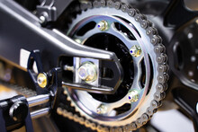 Close-up Of The Motorcycle Wheel Assembly, Swingarm Sprocket, And Rear Drive Chain That Powers The Engine