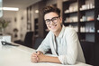 © Iryna - Confident and happy young guy with glasses in a modern office, exuding professionalism and positivity.