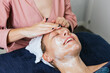 © ADDICTIVE STOCK CORE - Crop beautician cleansing face of woman in salon