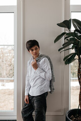 Wall Mural - portrait of handsome teenager standing near the window indoors and smiling at camera