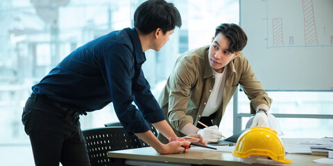 Wall Mural - Engineer team with construction work plan discussion together blueprint on working table in construction site with safety helmet