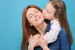 © New Africa - Portrait of happy mother and her cute daughter on light blue background. Space for text