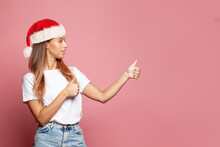 Young Woman In Santa Hat Showing Thumb Up
