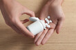 © New Africa - Man pouring pills from bottle at wooden table, top view