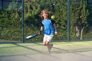 Wall Mural - Happy boy playing padel on court at daytime